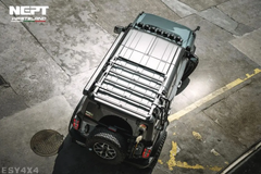 Top-down view of a black off-road vehicle with a metal rack on a textured pavement.