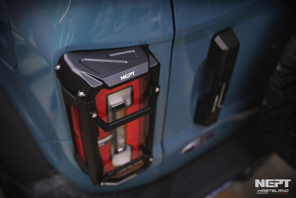 Close-up of a black and red NEPT tail light cover on a blue ford bronco, with NEPT branding.