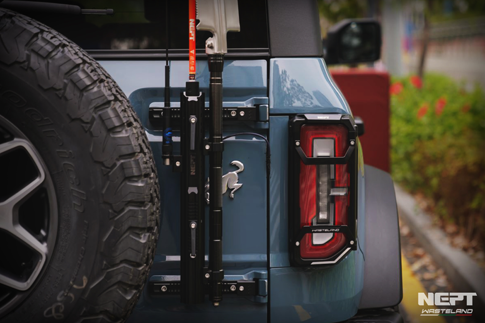 Close-up of a ford bronco with the flag pole mount by NEPT Wasteland  with a tire and tail light, blurred background